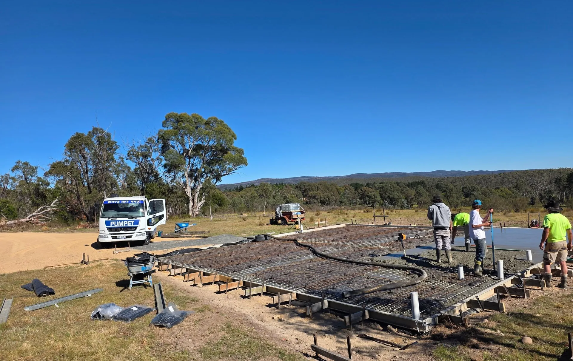 Multiple trucks and crew preparing a large mesh-reinforced slab for a bigger-scale commercial pour