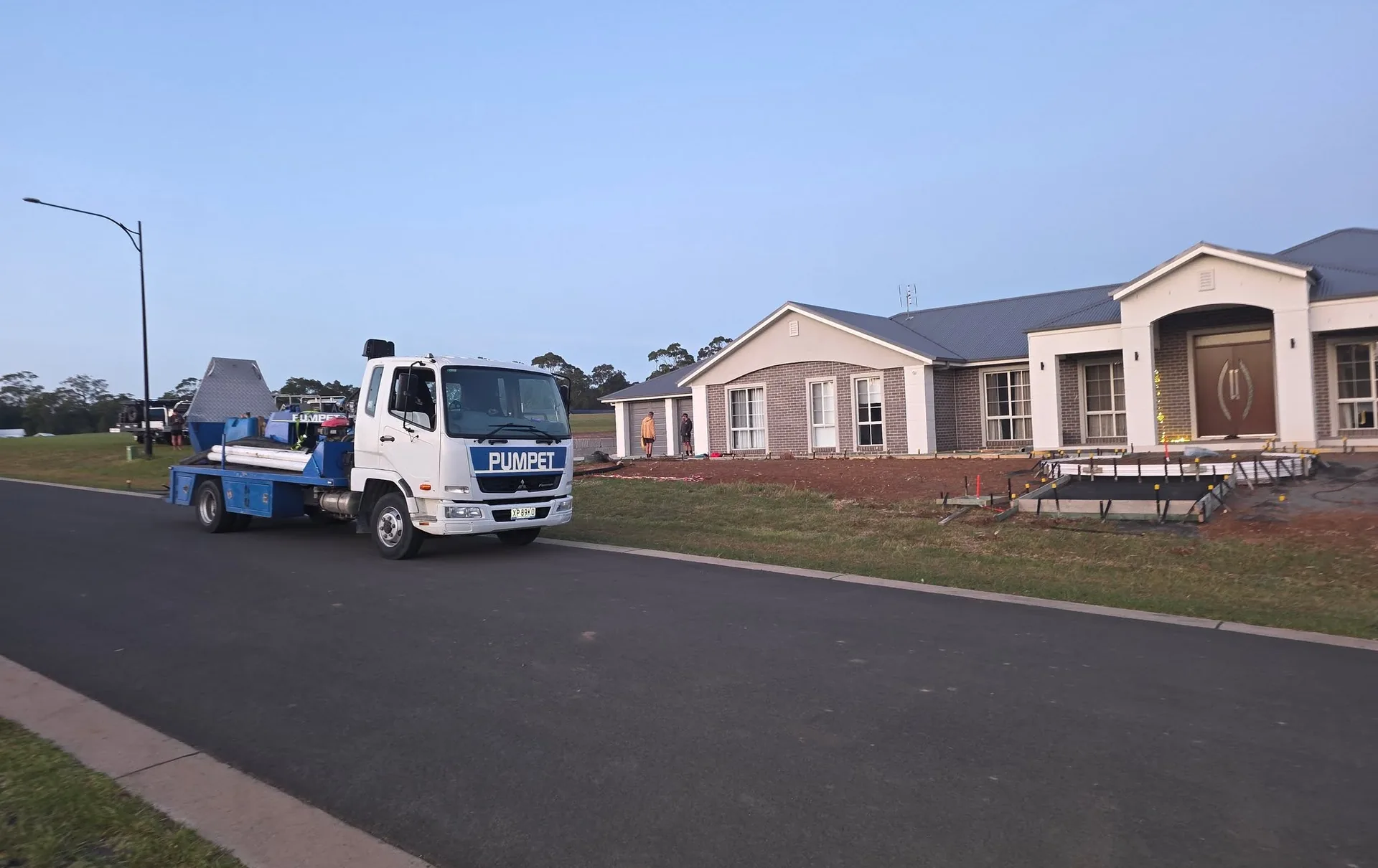 Pumpet concrete pump truck parked on a suburban Nowra street outside a large rendered brick home